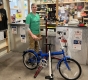 A man stands in front of a bike at the Ottawa Tool Library / Un homme se tient devant une bicyclette à l’Ottawa Tool Library.